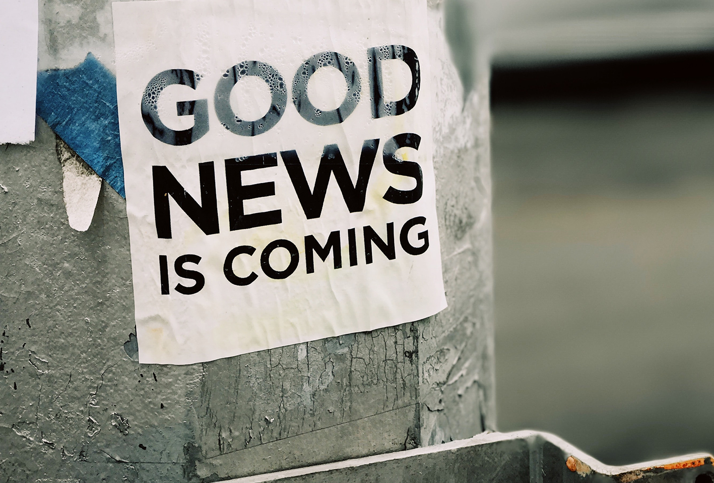 Poster on pole in street saying Good News is Coming