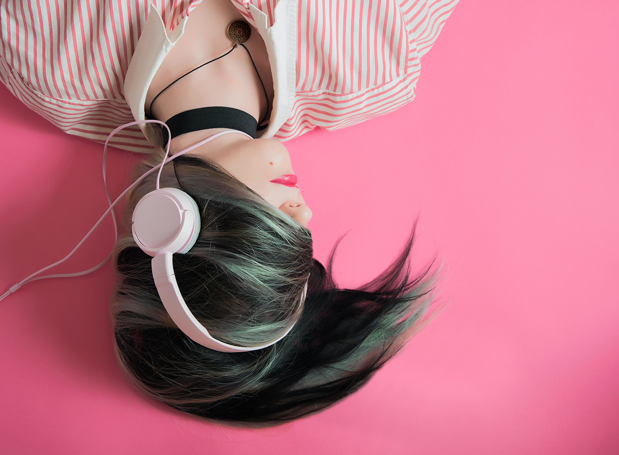 woman lying down with headphones and her hear covering her eyes