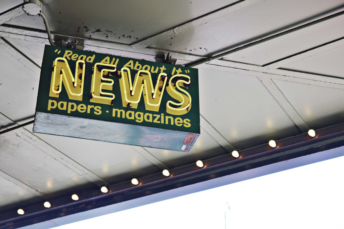 Advertisement sign under a roof saying News Read All About It